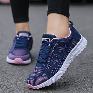 Navy running shoes with pink accents on a gray pavement background