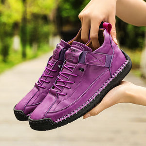 Purple sneakers held by a person with a blurred green background