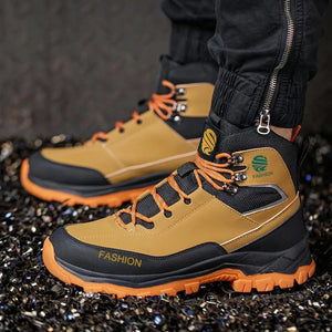 Tan and black safety boots with orange accents on a dark textured surface