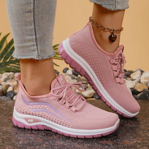Pink sneakers worn with light blue jeans on a natural stone surface.