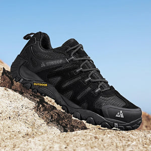 Black hiking boots with visible brand logo on a rocky surface