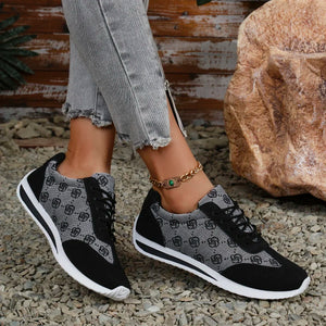 Person wearing black and gray patterned sneakers on a natural ground surface.