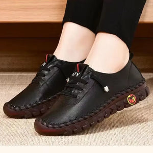 Black leather lace-up split leather casual flats with round toes and rubber outsoles with red soles on a textured surface
