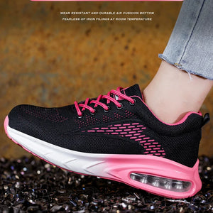 A black Women's Safety Work Shoes with bright pink laces, lining, and midsole accent, shown being worn on a person's foot against a textured brown background.