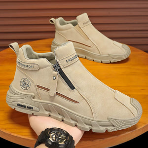 Beige ankle boots with zippers on a wooden surface, worn by a person.
