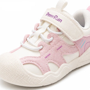 A close-up of a children's sneaker in off-white and light pink, featuring a hook-and-loop strap closure with a purple PmwRun logo, white laces, and a textured rubber toe cap.