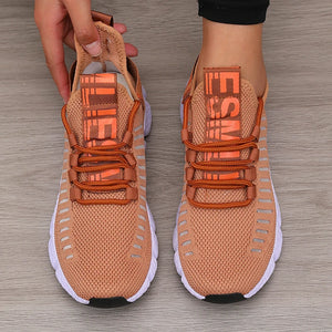 Pair of orange sneakers with brand logo on a wooden floor