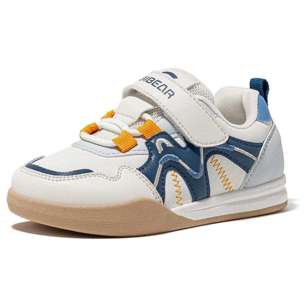 A children's white, navy, and blue athletic sneaker with orange accents, featuring hook-and-loop straps and a gum sole, shown on a white background.
