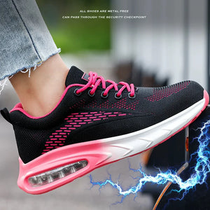 A close-up of a black Women's Safety Work Shoes with bright pink laces, pink trim, and a white midsole with a visible air cushion unit. The shoe is being worn on a person's foot, with cropped denim jeans visible.