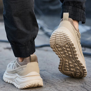 Beige safety work shoe sneakers with white soles worn by a person on a concrete surface