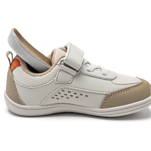 A toddler's low-top sneaker in off-white and beige, featuring a hook-and-loop strap closure, mesh panels, perforated detailing, and a pull tab on the heel.