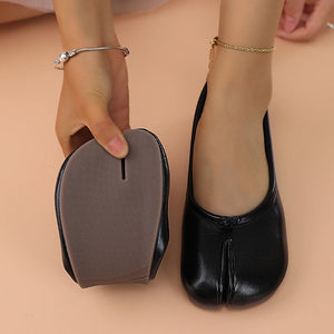 Black ballet flats with a shoe tree on a beige background