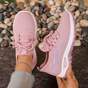 Pink athletic shoes with white soles on a pebble surface