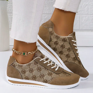 Brown patterned sneakers with white soles worn by a person on a white background