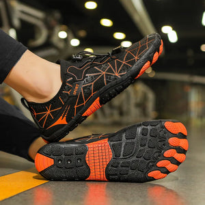 Black and orange athletic shoes with unique sole design on a blurred indoor background