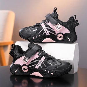 A pair of black and pink children's sneakers displayed on a white box against a softly blurred indoor background. The shoes feature hook-and-loop straps, textured synthetic panels, and decorative text accents including 'SINCE 1986' and 'SIGMA'.