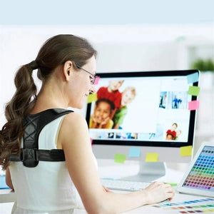 Woman wearing a back brace while using a computer Adjustable upper back support strap for shoulder alignment and daily posture comfort