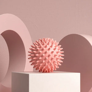 Pink textured ball on a white platform with a pink geometric background