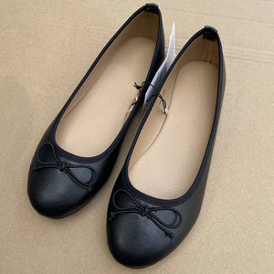 Pair of black shoes with a bow on a beige background