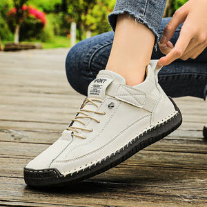 White Slip-On Shoes with black sole on a wooden floor, person wearing jeans.