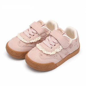 A pair of PmwRun toddler sneakers in a light pink color, featuring lace-up front, hook-and-loop straps, delicate lace trim, and brown rubber soles, shown on a white background