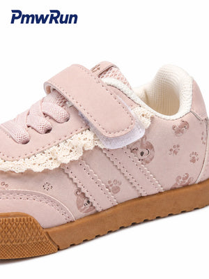 A light pink children's sneaker with a hook-and-loop strap, lace detail, paw print pattern, and a brown rubber sole