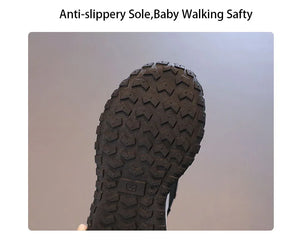 Close-up of a black textured anti-slip sole with deep tread patterns, held against a plain gray background with text at the top reading 'Anti-slippery Sole,Baby Walking Safty'.