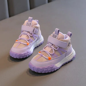 A pair of children's mid-top sneakers in pastel lavender and beige, featuring hook-and-loop strap closures, lace-up front details, and chunky textured soles, displayed on a gray surface.