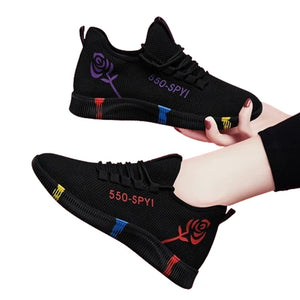 Black sneakers with colorful accents held by a hand on a white background