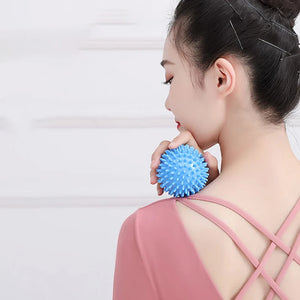Woman holding a blue spiky ball against her shoulder on a plain background
