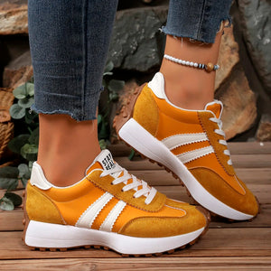Yellow sneakers with white stripes worn by a person on a wooden surface.
