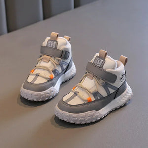 A pair of children's low-top sneakers in white and gray with small orange accents, displayed on a gray textured surface.