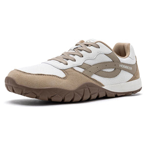 A low-top athletic sneaker in white, beige, and brown, featuring a white mesh upper, beige suede overlays, a beige side stripe with 'HOGUECTOR' branding, beige laces, and a brown textured outsole, shown on a white background.