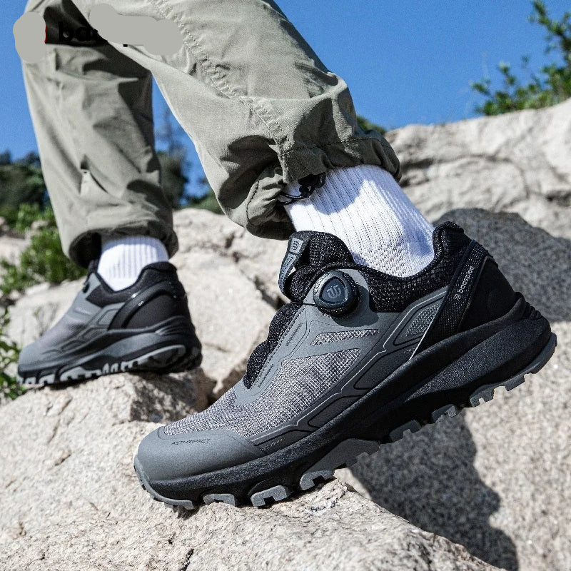 Person wearing black hiking shoes on a rocky surface with a clear blue sky.