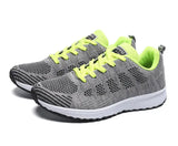 Gray running shoes with neon green laces on a white background