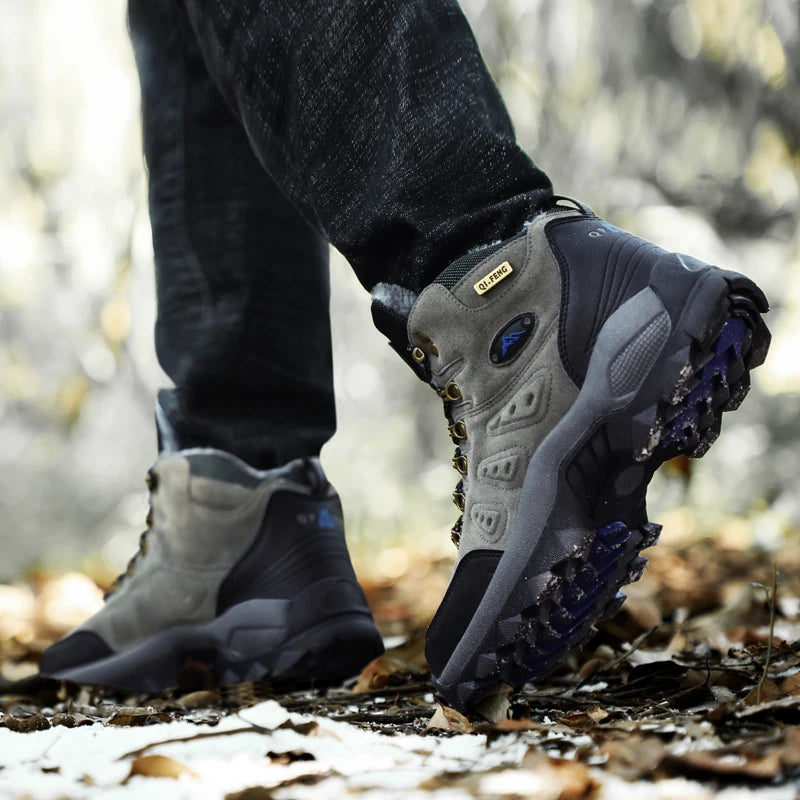 Person wearing gray hiking boots with blue soles on a forest path
