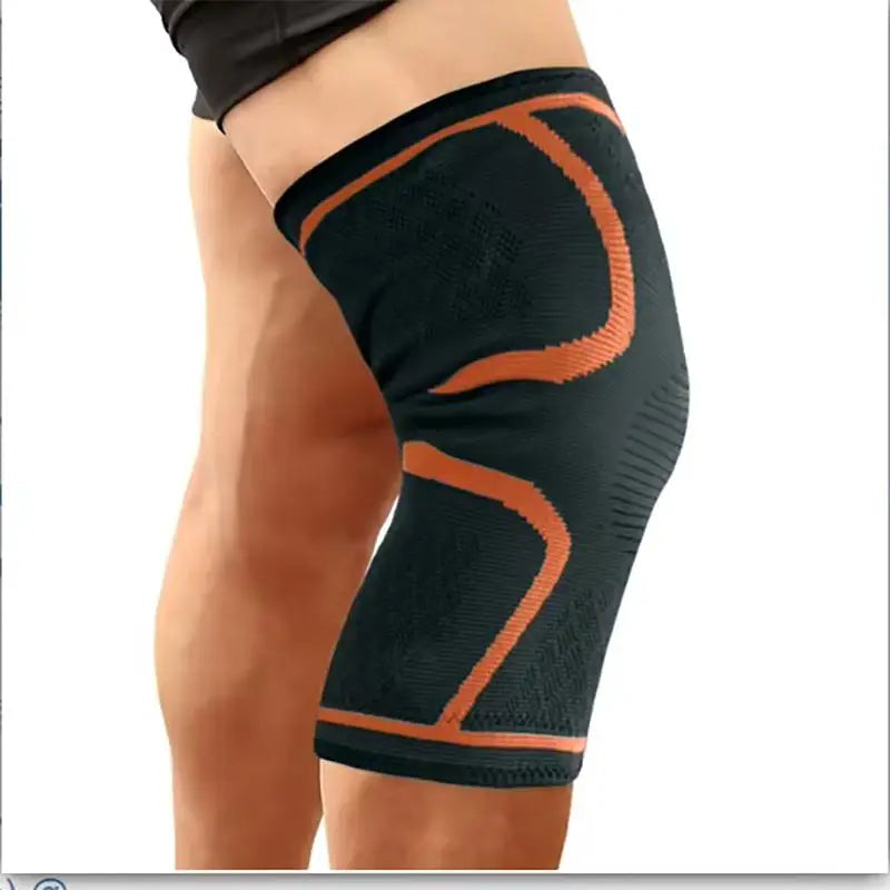 Black knee brace with orange accents on a person's knee, labeled 'Orange'.
