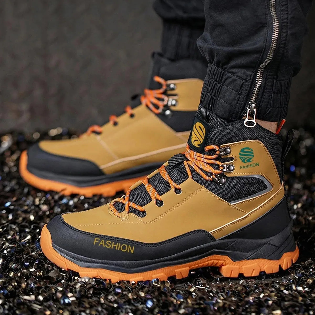 Tan and black safety boots with orange accents on a dark textured surface