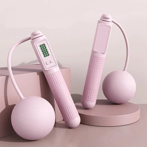 Pink electronic device with digital display on a pink platform against a light pink background.