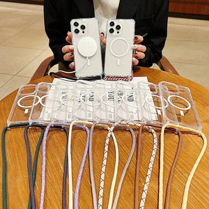 Person holding two phones with clear cases on a wooden table with additional iphone cases and straps.
