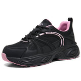 A black women's work shoes sneaker with pink accents, featuring a breathable mesh upper, black laces, a pink inner lining, and a chunky black sole with pink detailing, shown against a plain white background.