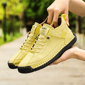 Yellow sneakers held by a hand with a blurred green outdoor background