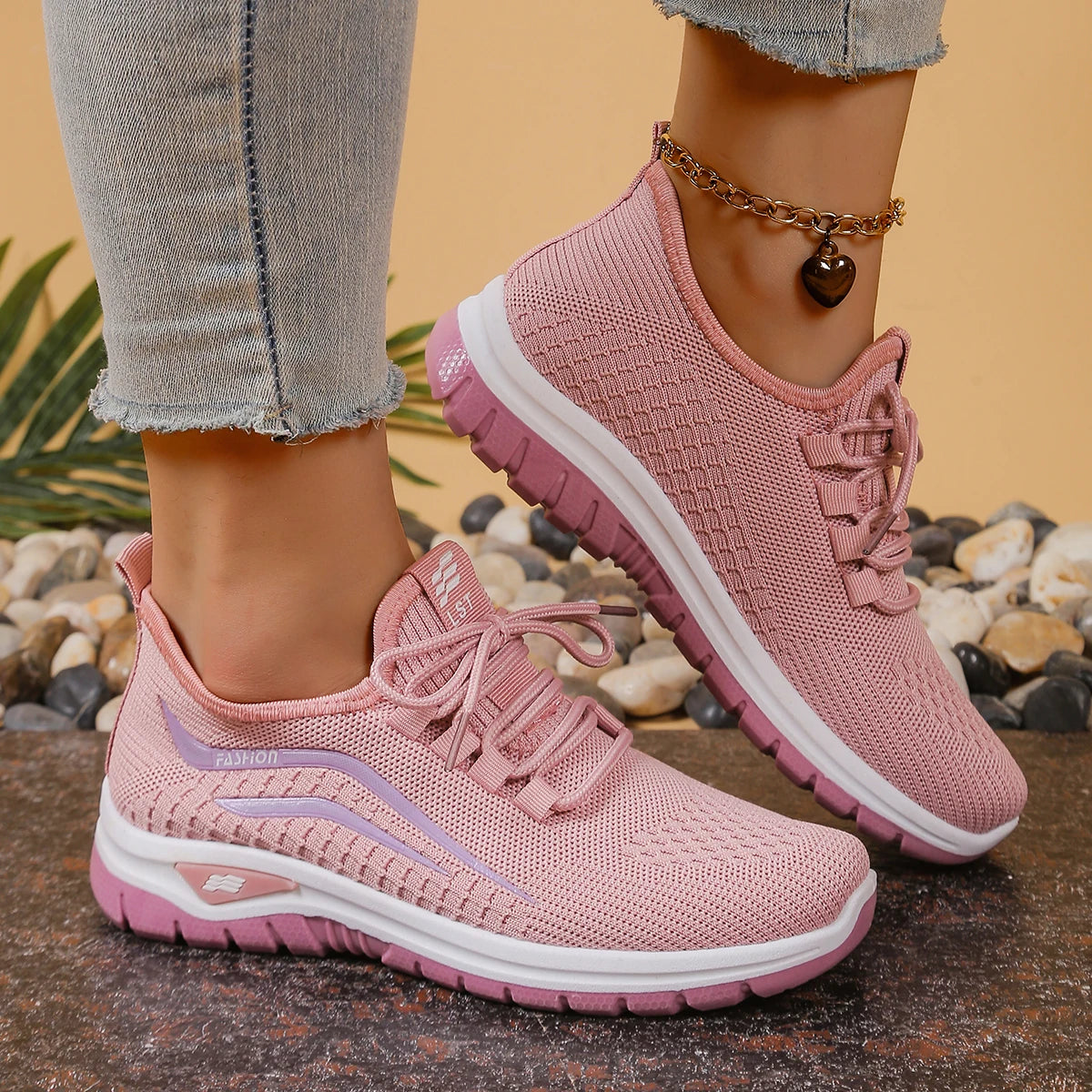 Pink sneakers worn with light blue jeans on a natural stone surface.