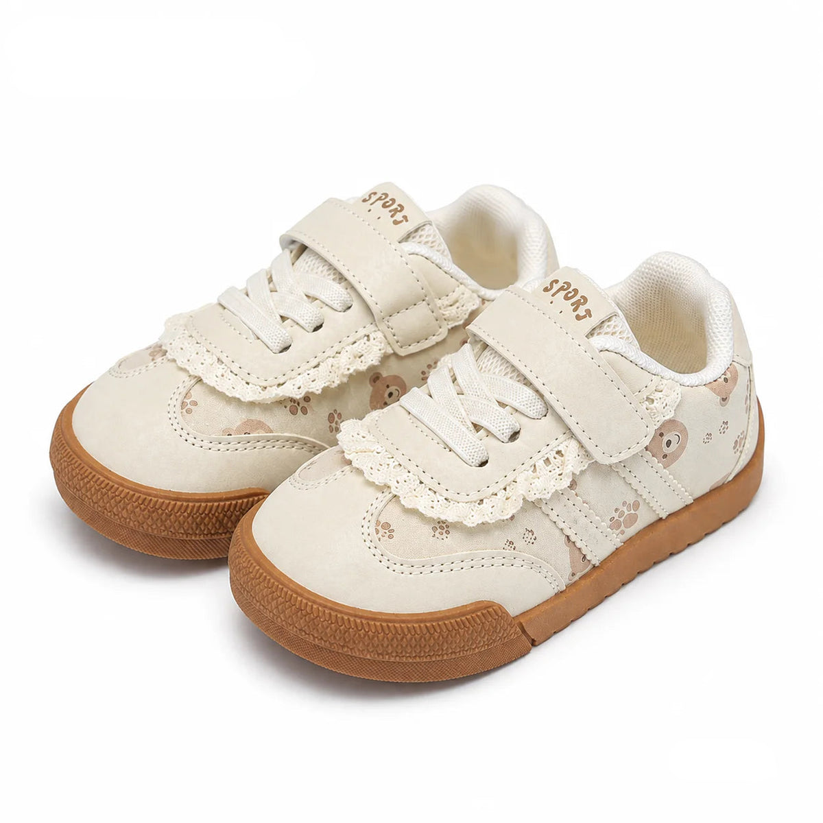 A pair of toddler sneakers in cream canvas with lace trim, hook-and-loop straps, and brown rubber soles, shown on a white background.