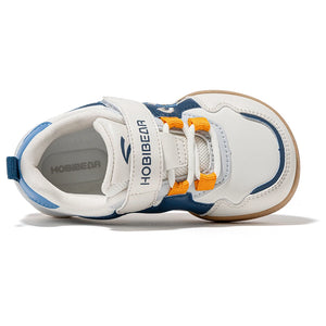 A children's white sneaker with navy blue panels, orange laces, and a tan outsole, shown from a side profile on a white background. The brand name HOBIBEAR is visible on the strap and the inner sole.