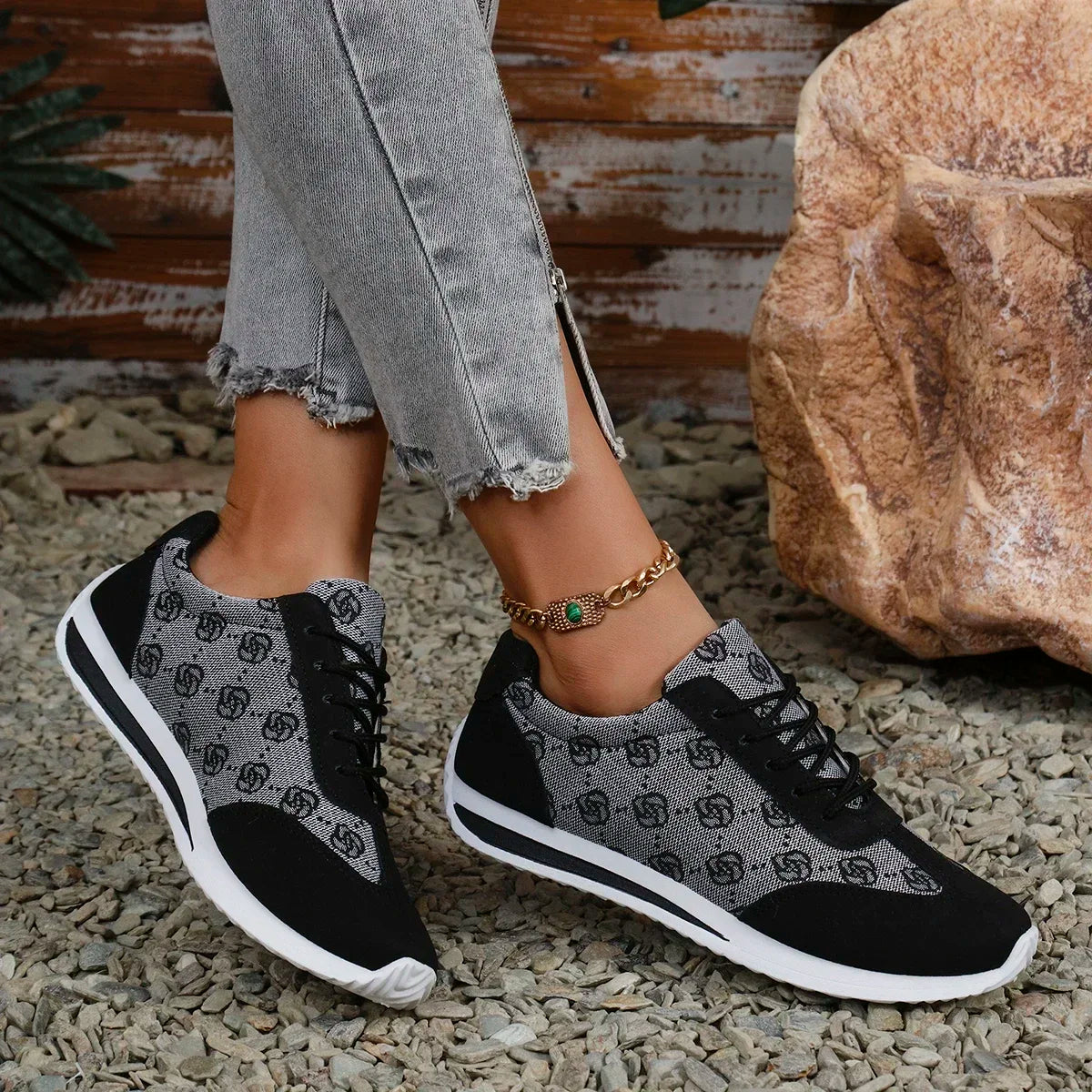 Person wearing black and gray patterned sneakers on a natural ground surface.