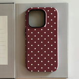 iPhone case with white polka dots on a red background, placed on an open book.