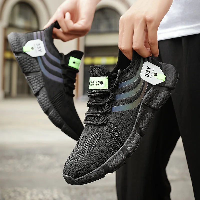 Person holding black athletic shoes with visible brand tags.
