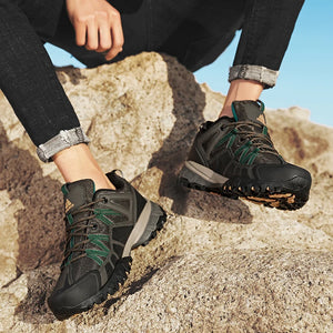 Person wearing black and green hiking boots on a rocky surface
