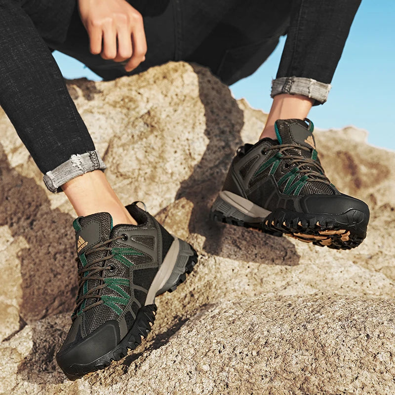 Person wearing black and green hiking boots on a rocky surface